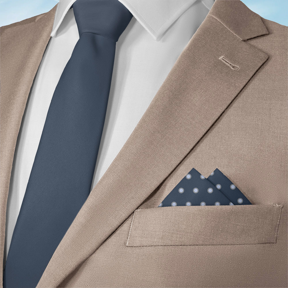 Close-up of a beige suit with a navy tie and matching dots pocket square.