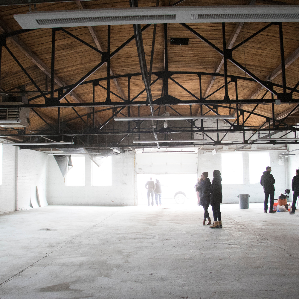 people standing in an empty manufacturing space