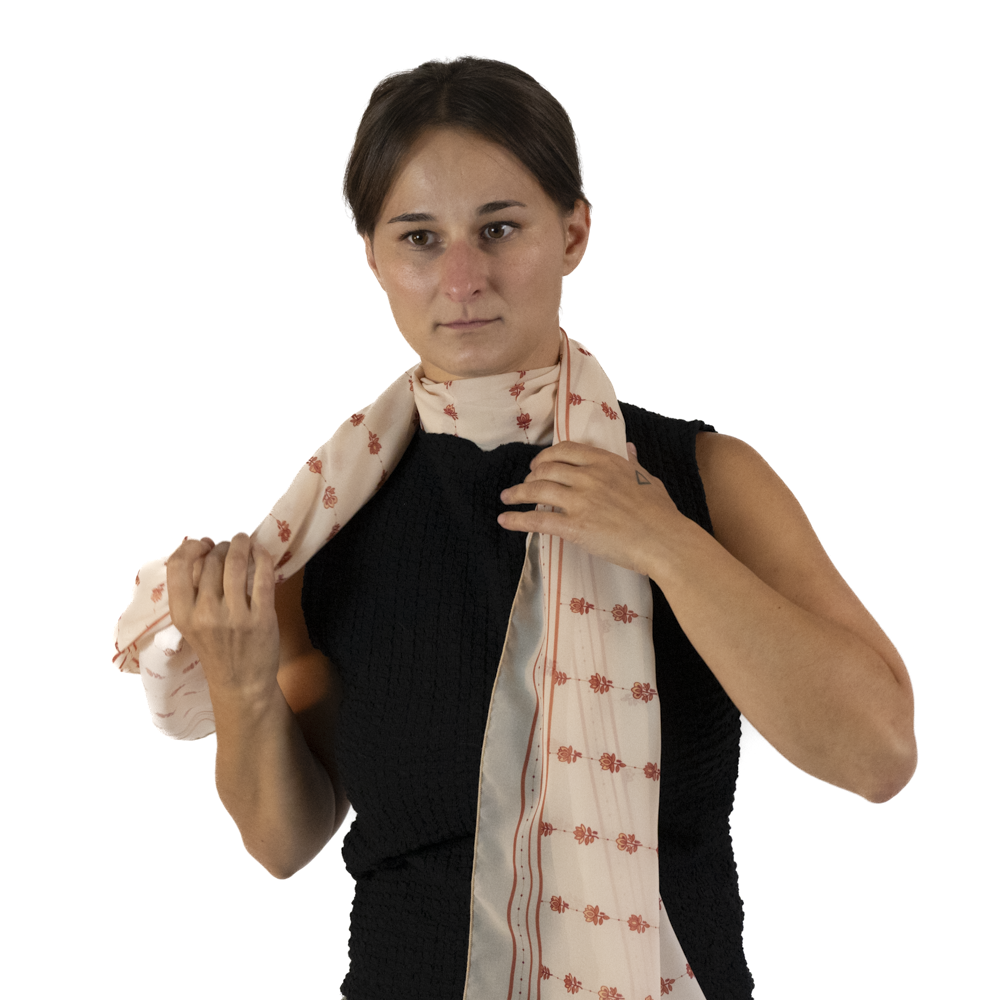 A woman wraps the ends of a rectangle scarves around her neck on both sides.