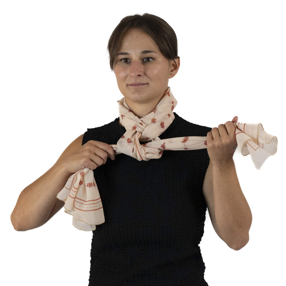 A woman tying a knot in the scarf around around her neck and holding the ends out.