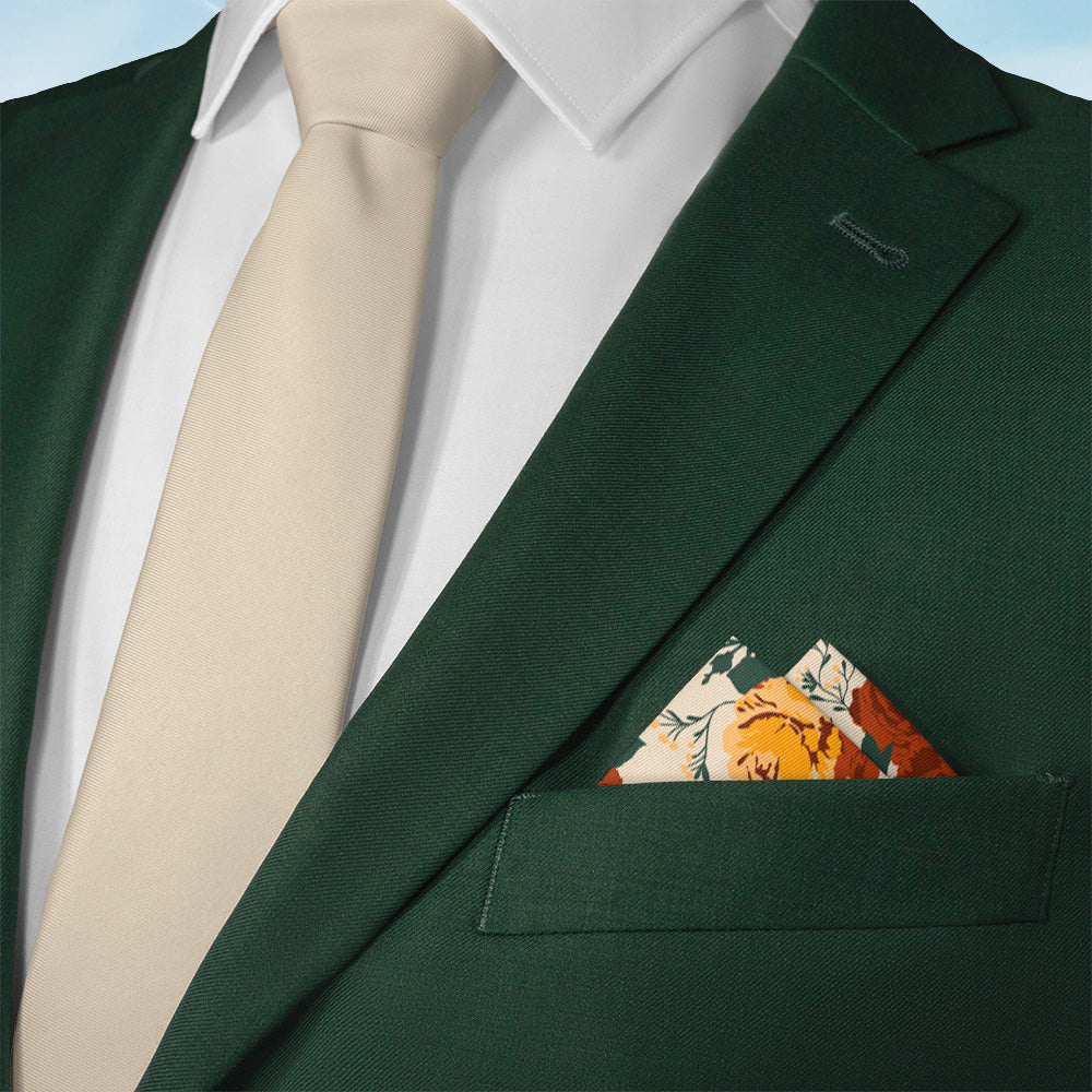 Green suit with beige tie and floral pocket square against a blue sky background