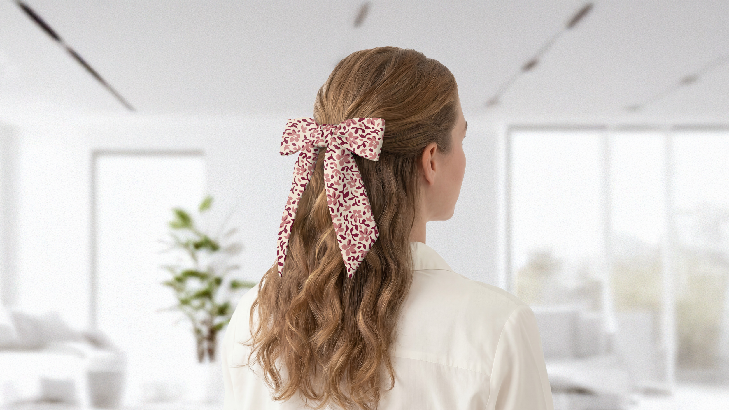 Person with long hair tied back with a decorative pink scarf bow in an indoor setting