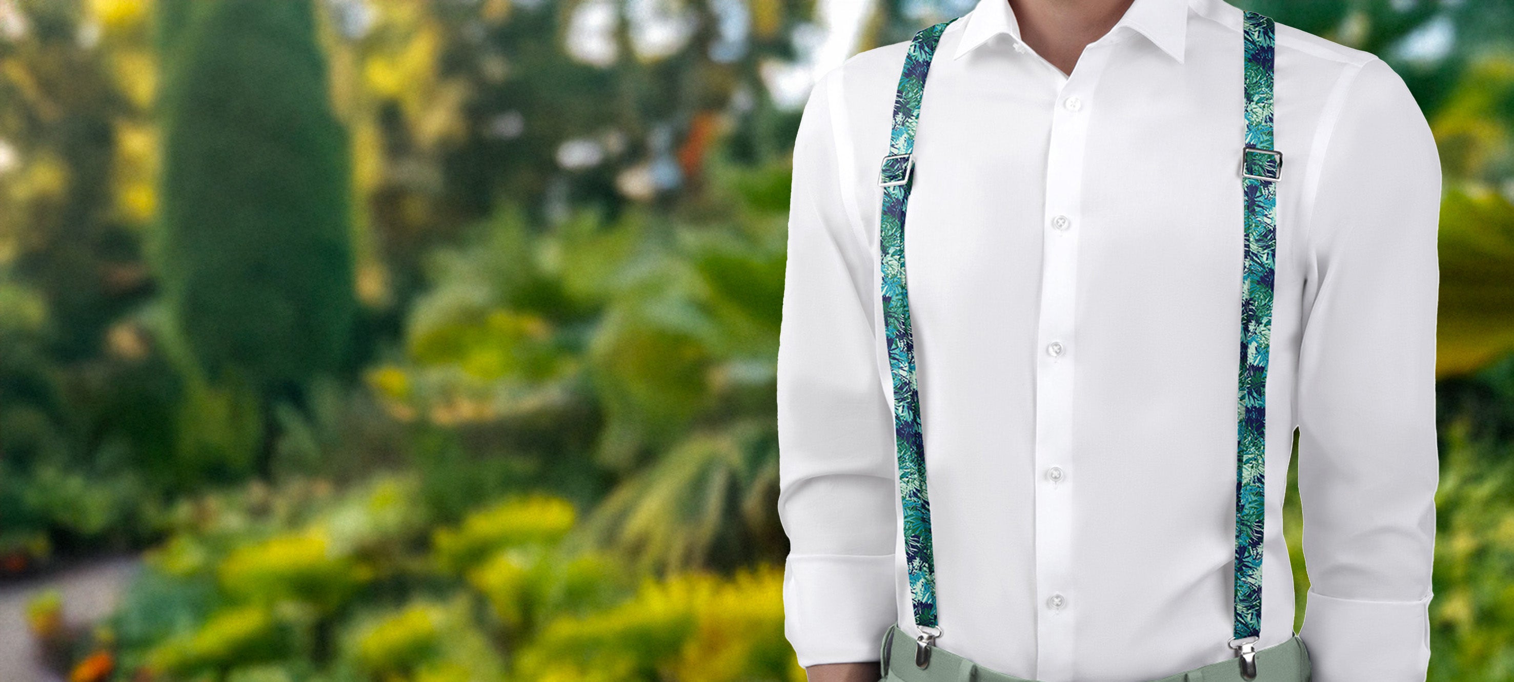 Person wearing a white shirt and green floral suspenders with a blurred garden background