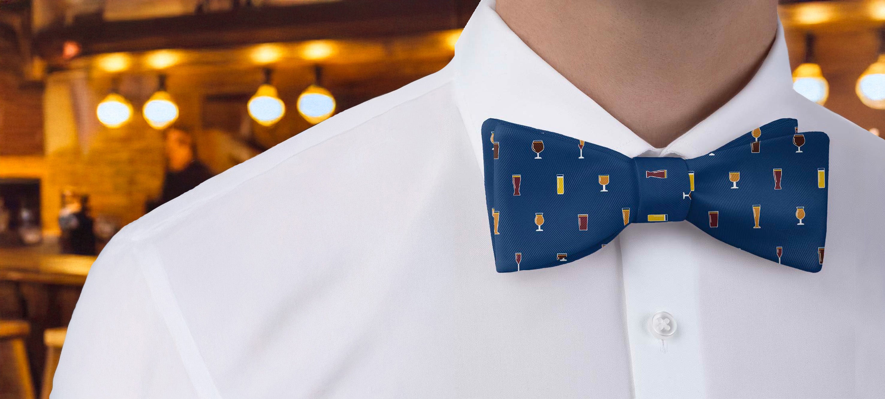 Person wearing a white shirt with a blue bow tie featuring beer glass icons in an indoor setting.