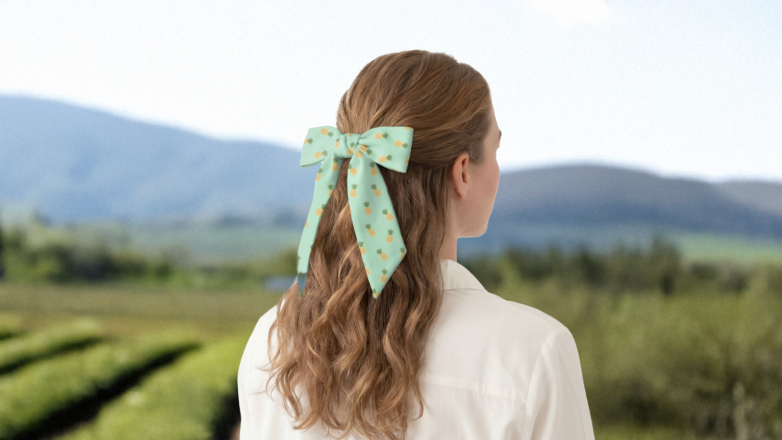Person with a green hair scarf bow looking at a scenic landscape
