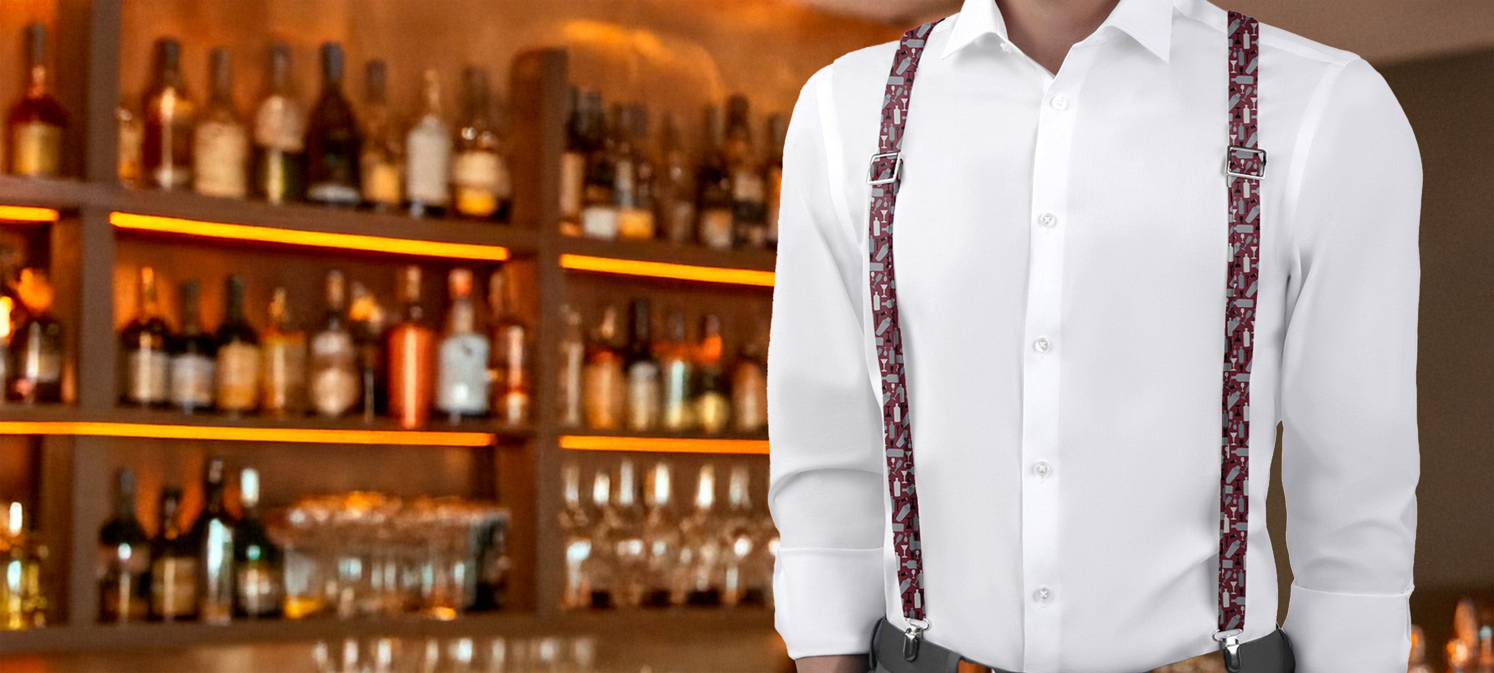 Person wearing a white shirt and cocktail-themed suspenders in a bar setting