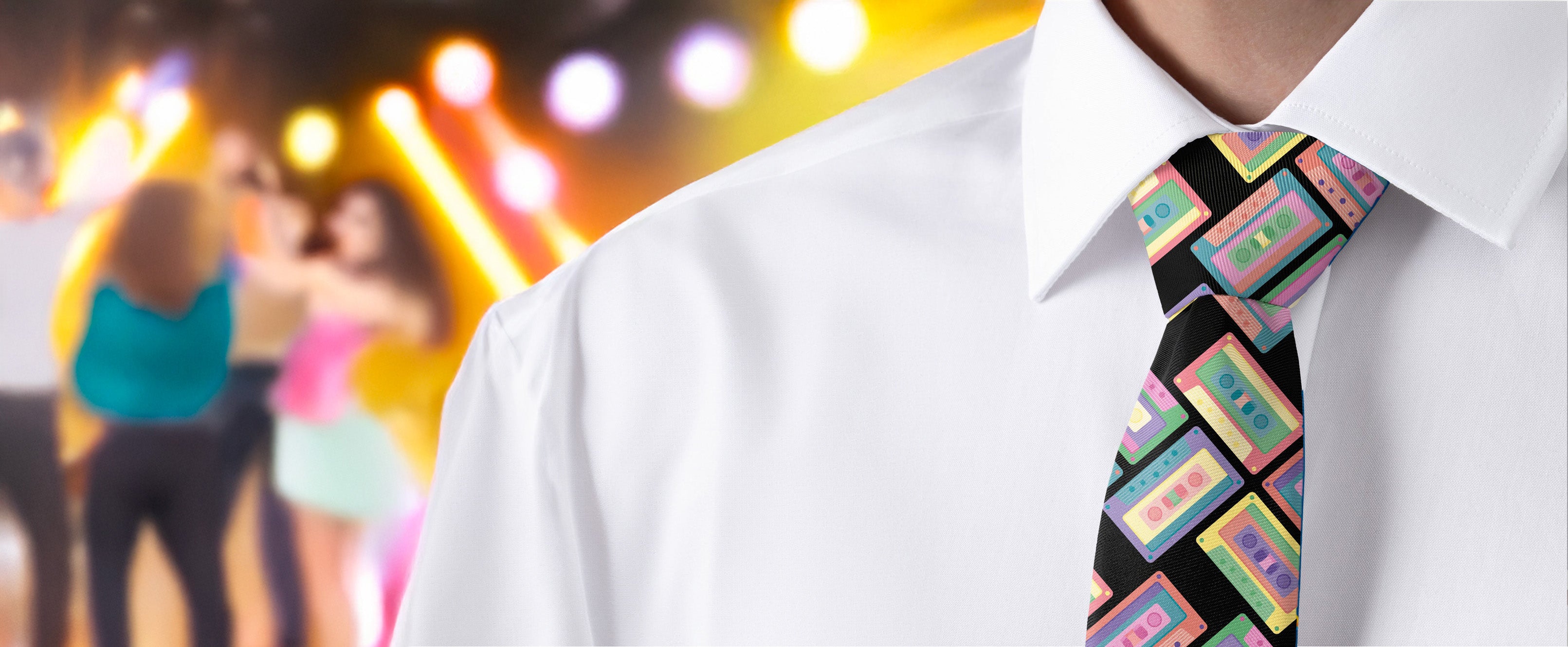 Person wearing a white shirt and colorful cassette tie with a blurred background of people and lights.