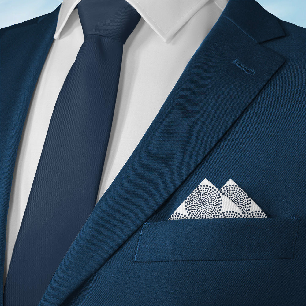 Navy blue suit with white shirt, dark blue tie, and geometric pocket square on a light blue background