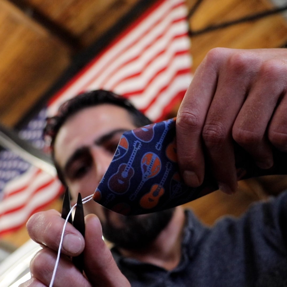 Man trimming a necktie in American manufacturing space