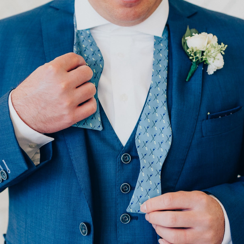 Man wearing a blue suit with a patterned vest and white shirt, holding his jacket open.