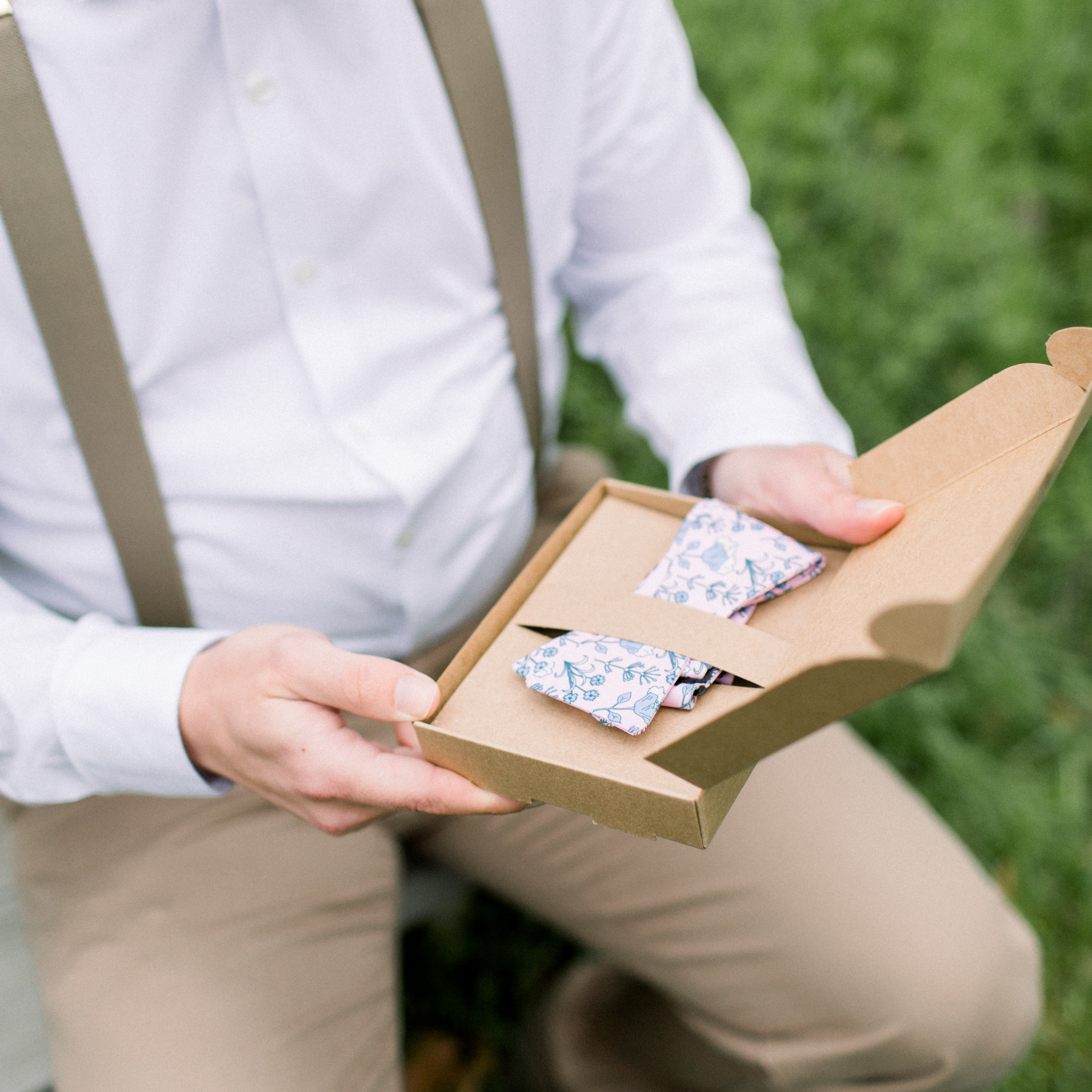 Man opening bow tie box with floral bow tie