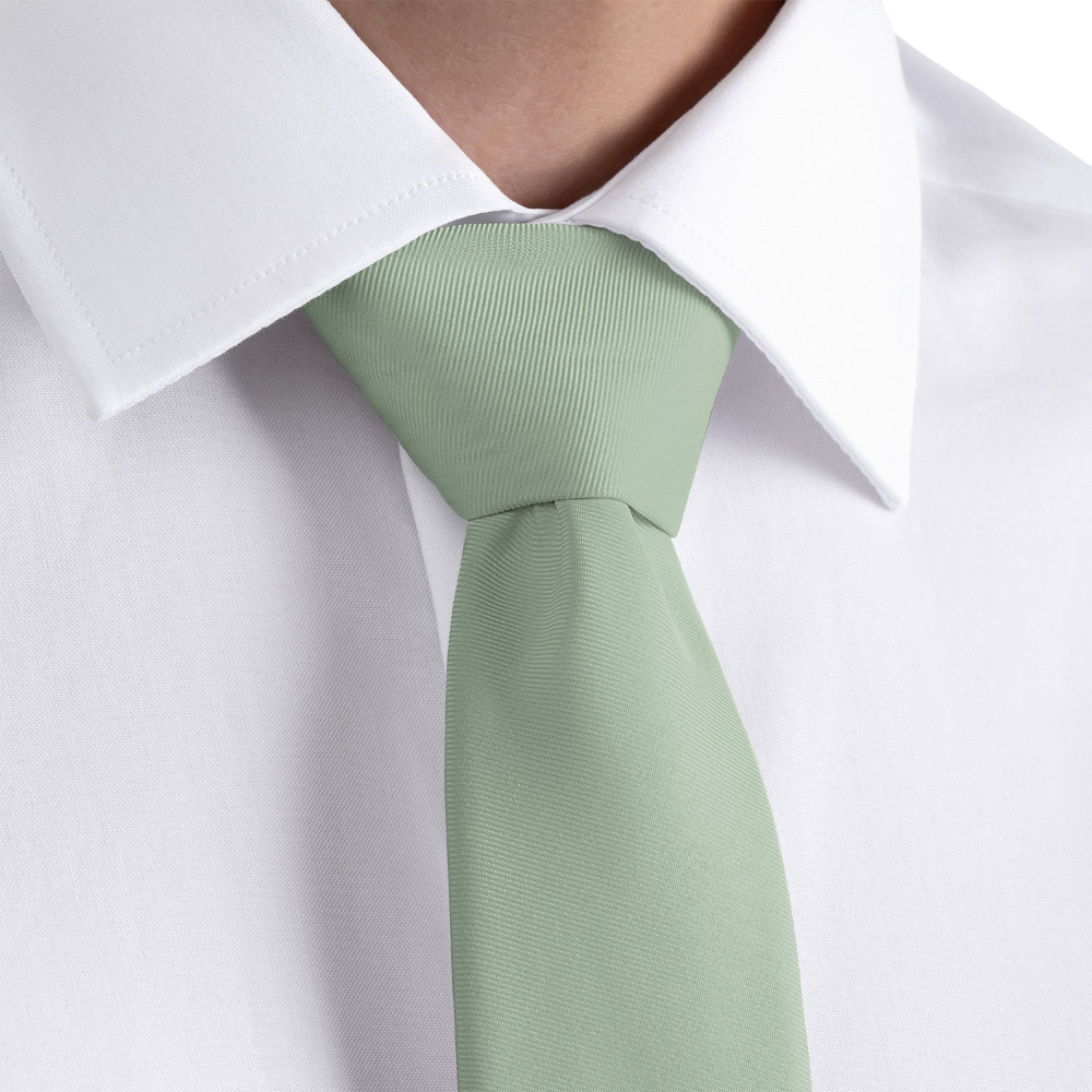 Light green tie worn with a white shirt on a plain background