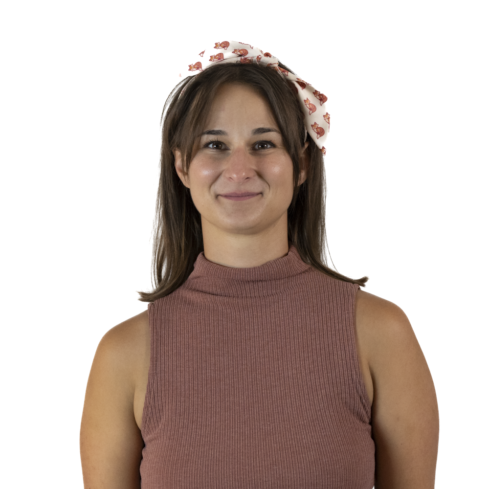 A woman wearing a cream hair scarf as a headband with scarf ends tied on top of head