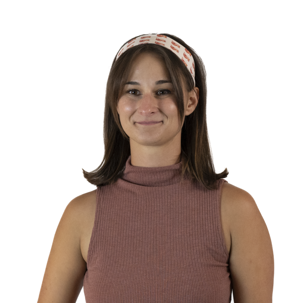 A woman with brown hair wearing a patterned cream hair scarf as a head band.