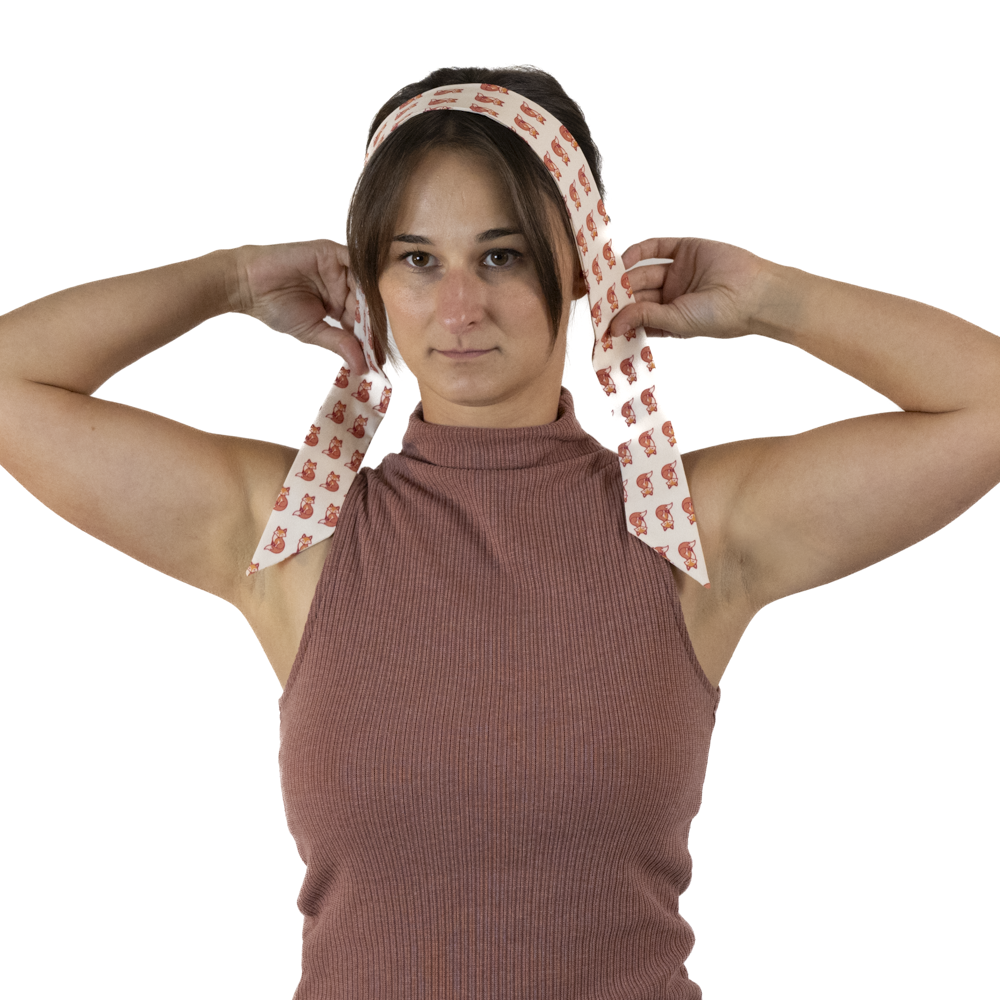 A woman placing a skinny scarf over her head.