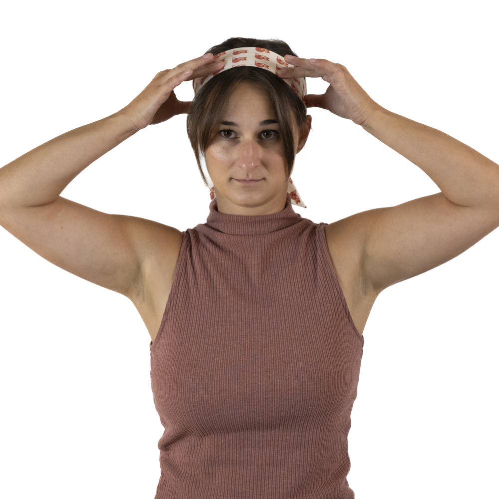 A woman adjusting a hair scarf on her head with both hands.