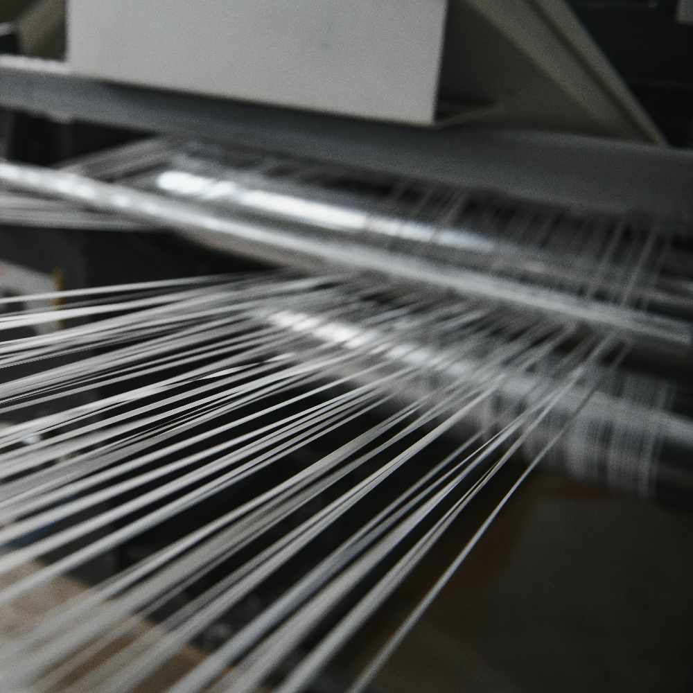 Close-up of a loom with threads being woven.