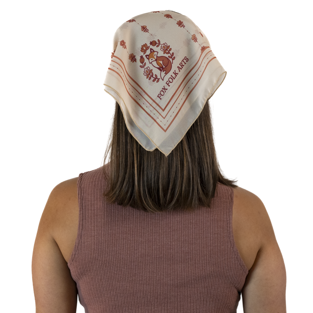 A woman viewed from behind wearing a cream-colored square scarf as a headscarf.