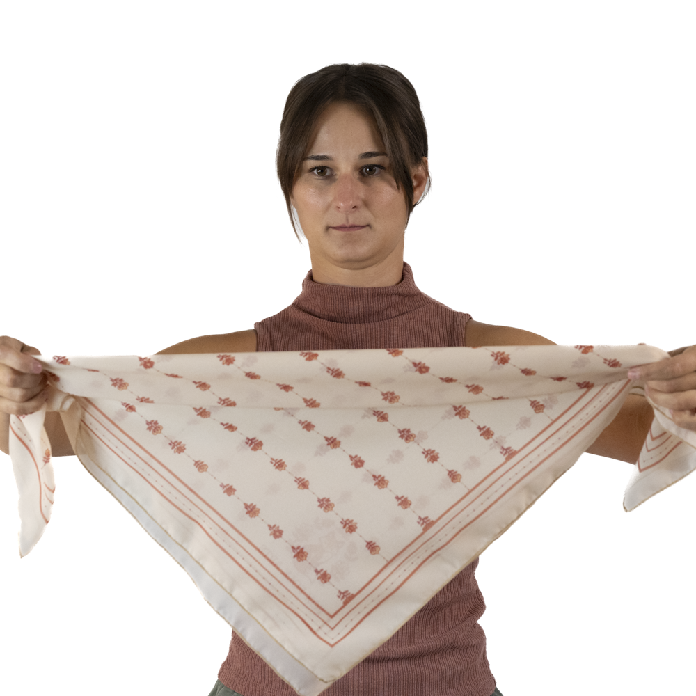Woman folding a square scarf into a triangle by bringing the two opposite corners together.