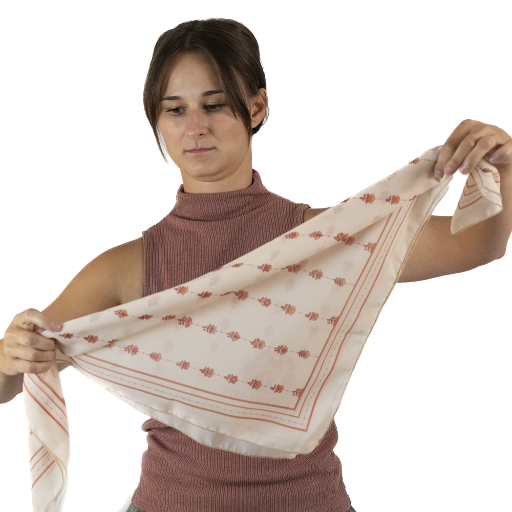 A woman folding a square scarf to be a smaller triangle shape.
