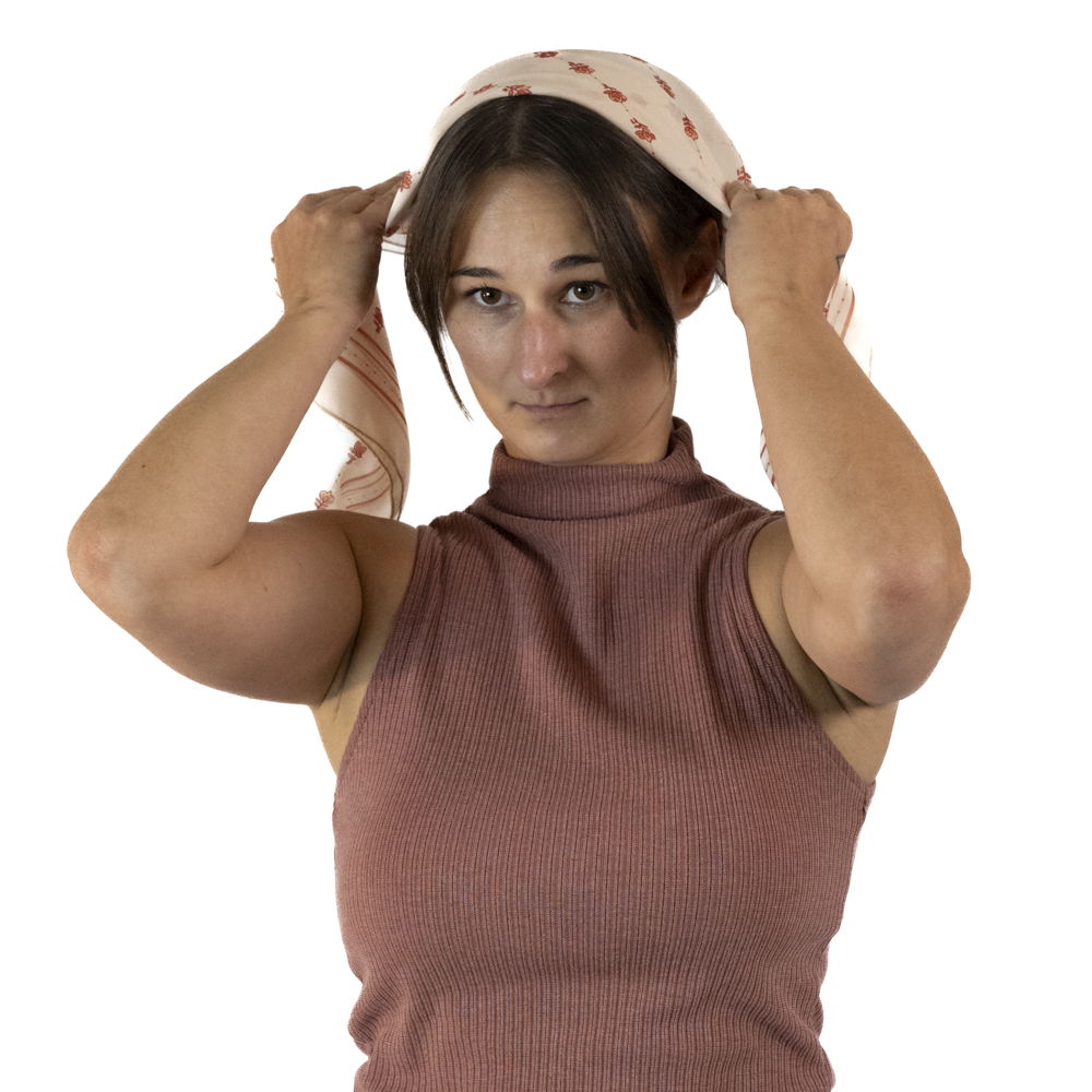A woman placing a triangle shaped scarf onto the crown of her head
