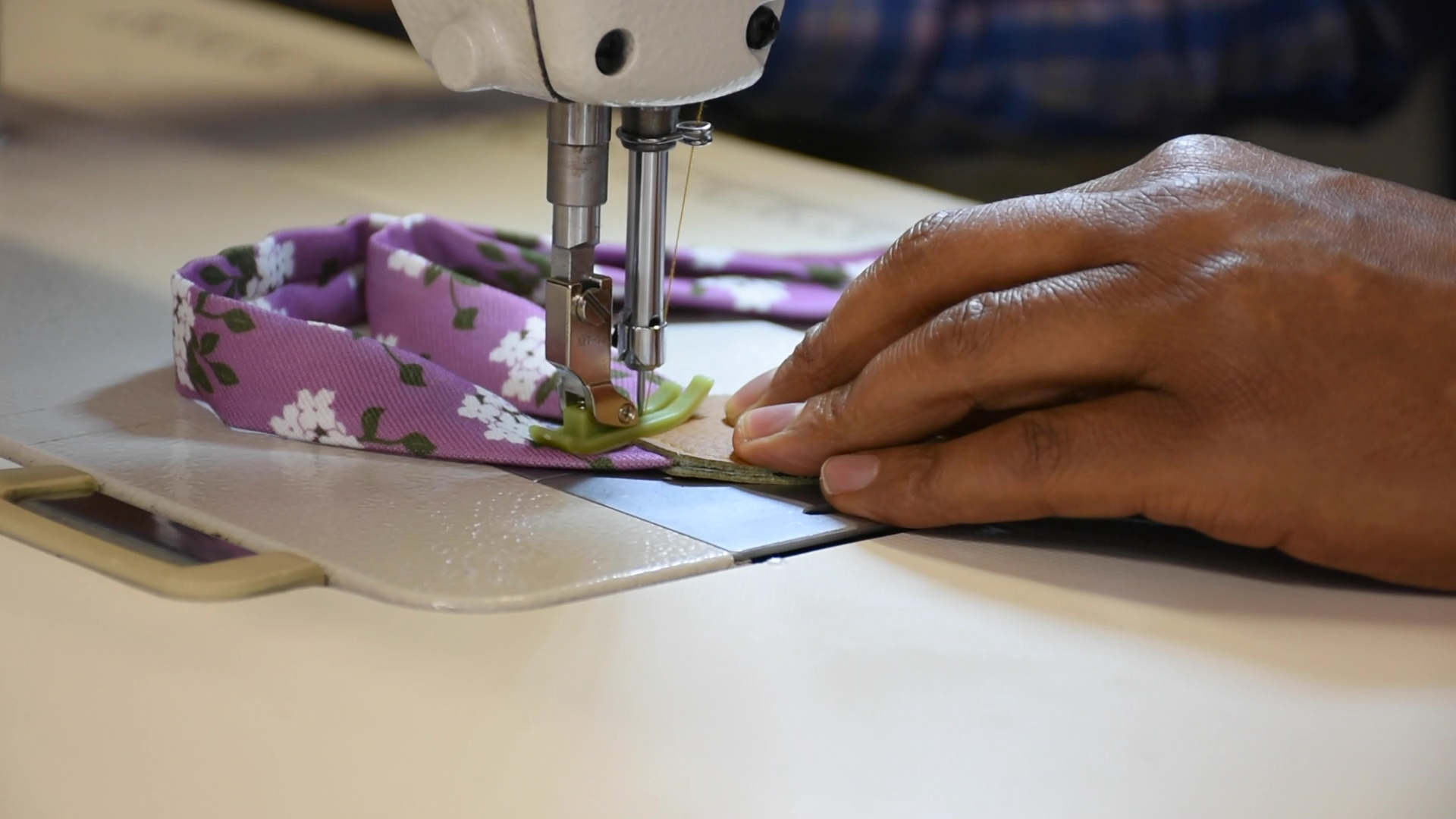Person using a sewing machine to work on a purple fabric item.