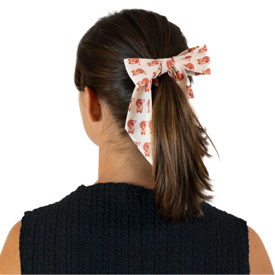 A woman shown from the back wearing a ponytail with a hair scarf tied into a bow.