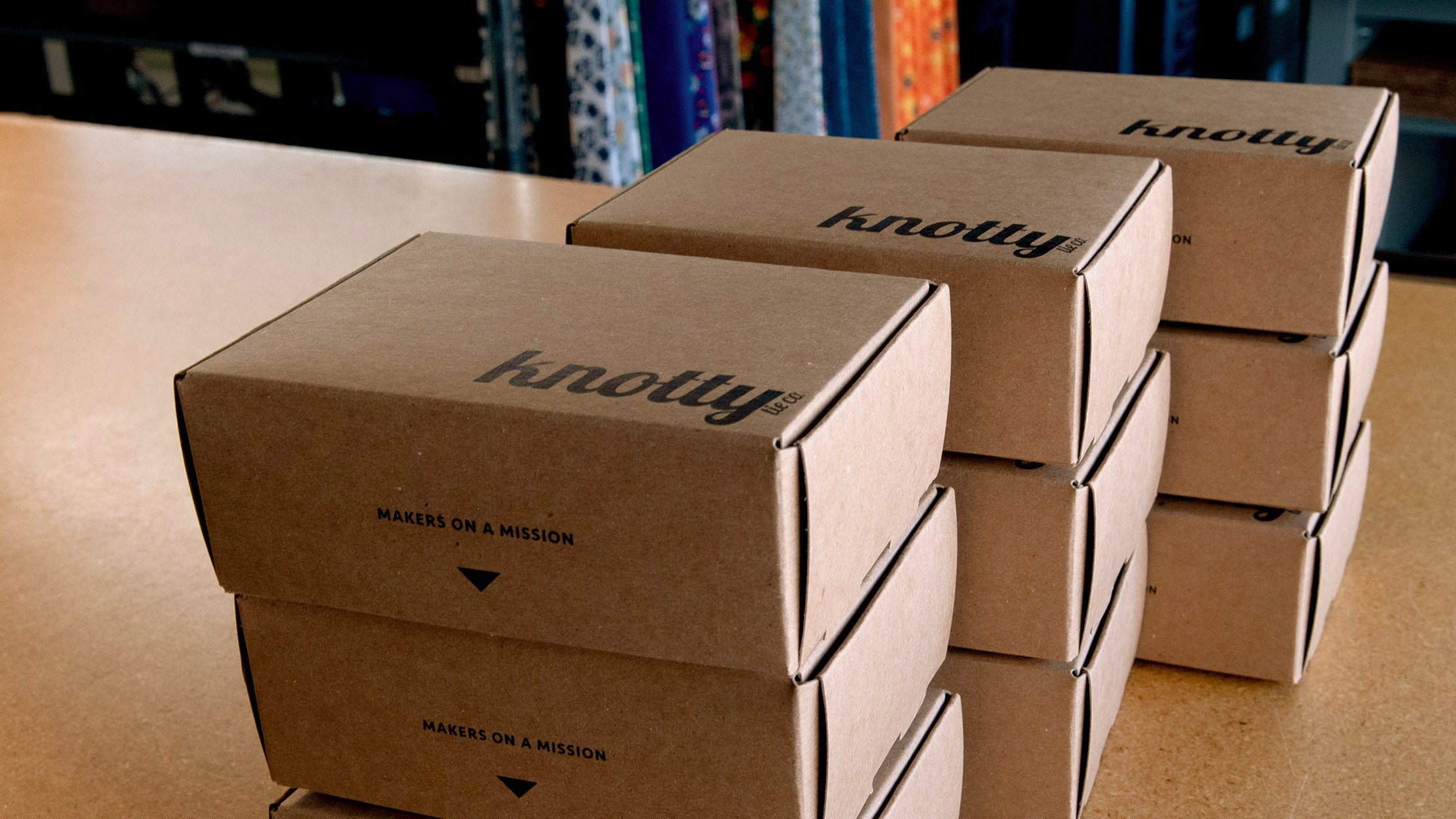 Stack of brown kraft paper boxes with 'knotty' branding on a wooden surface.