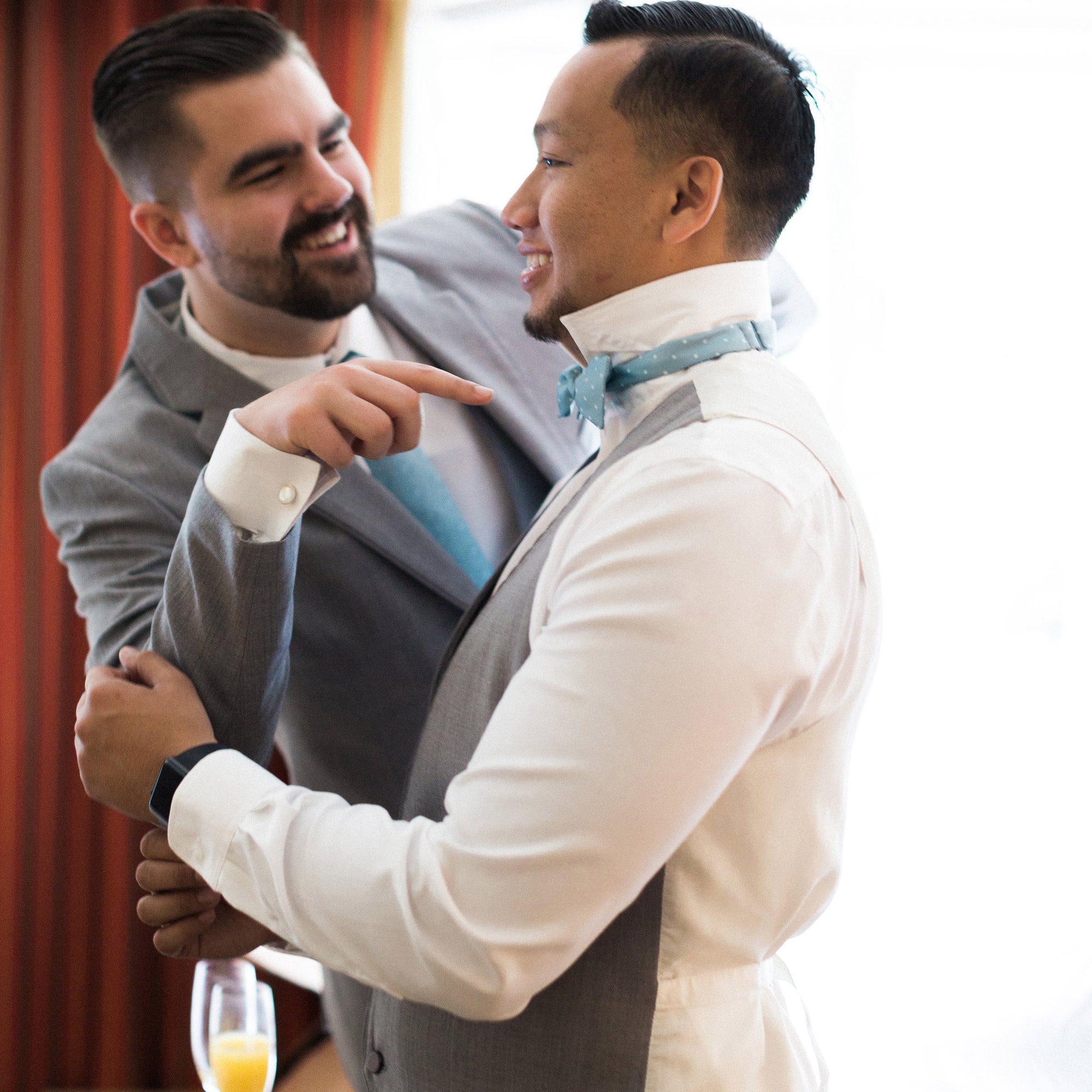 Groomsman helping groom tie bow tie