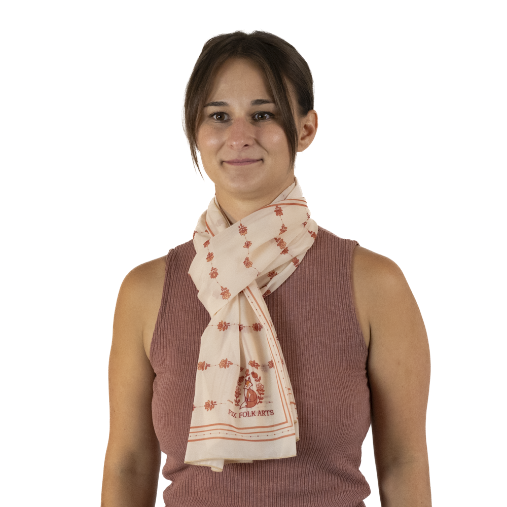 A woman wearing a cream-colored scarf in a Parsian knot or European loop style.