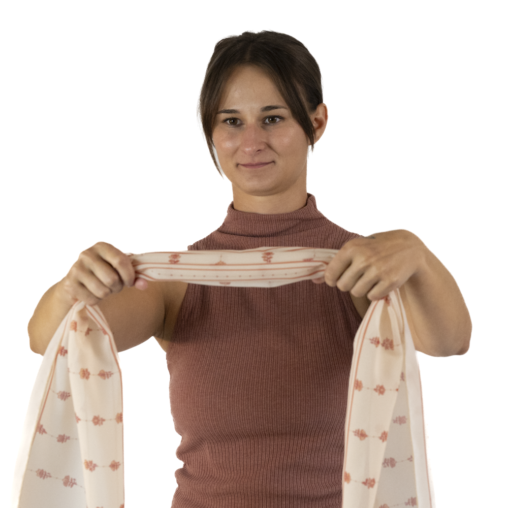 A woman holds up a gathered cream rectangle scarf.