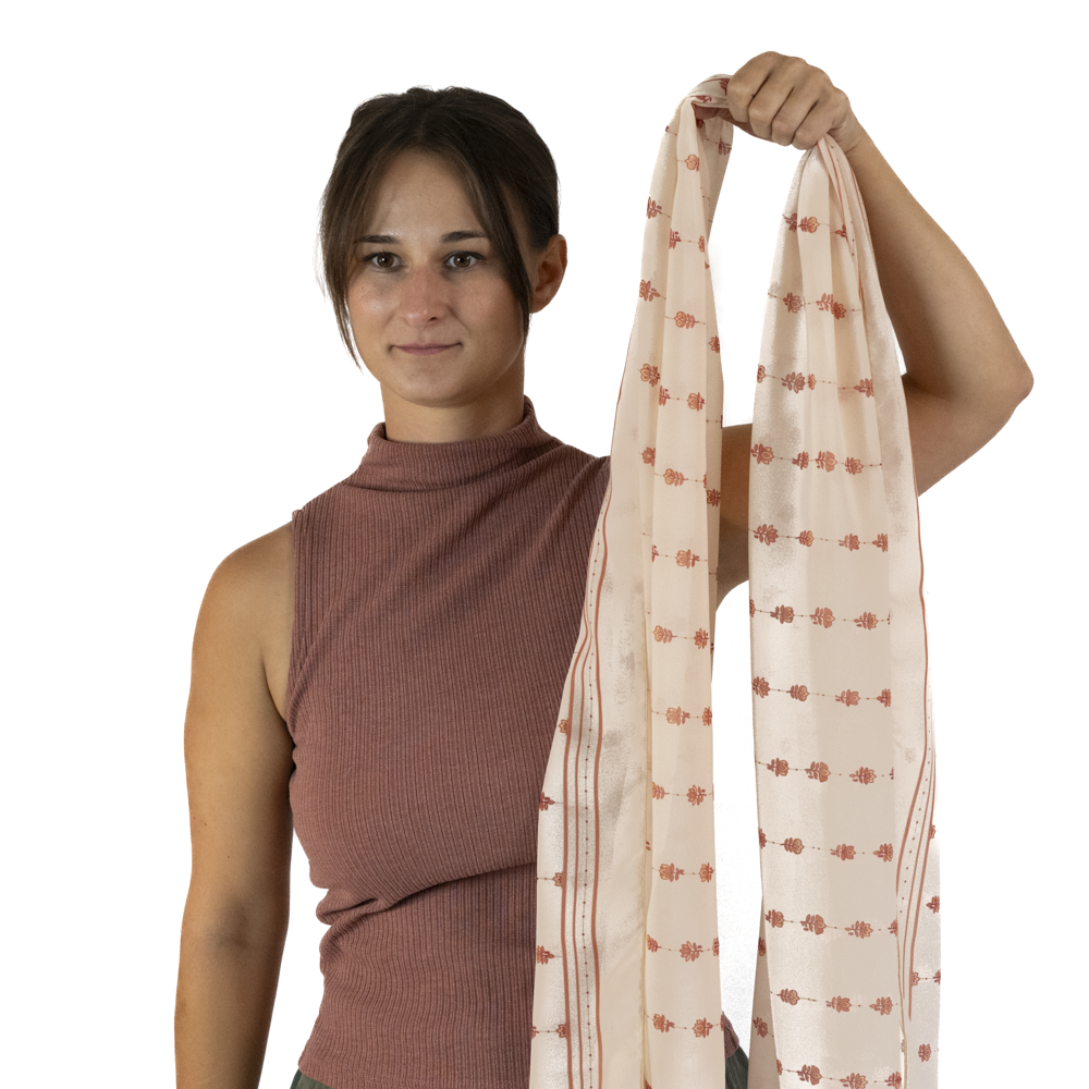 A woman holds up a long cream-colored rectangle scarf 