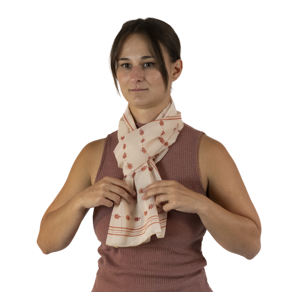 A woman adjusting a cream rectangle scarf tied as a parisian knot or european loop around her neck