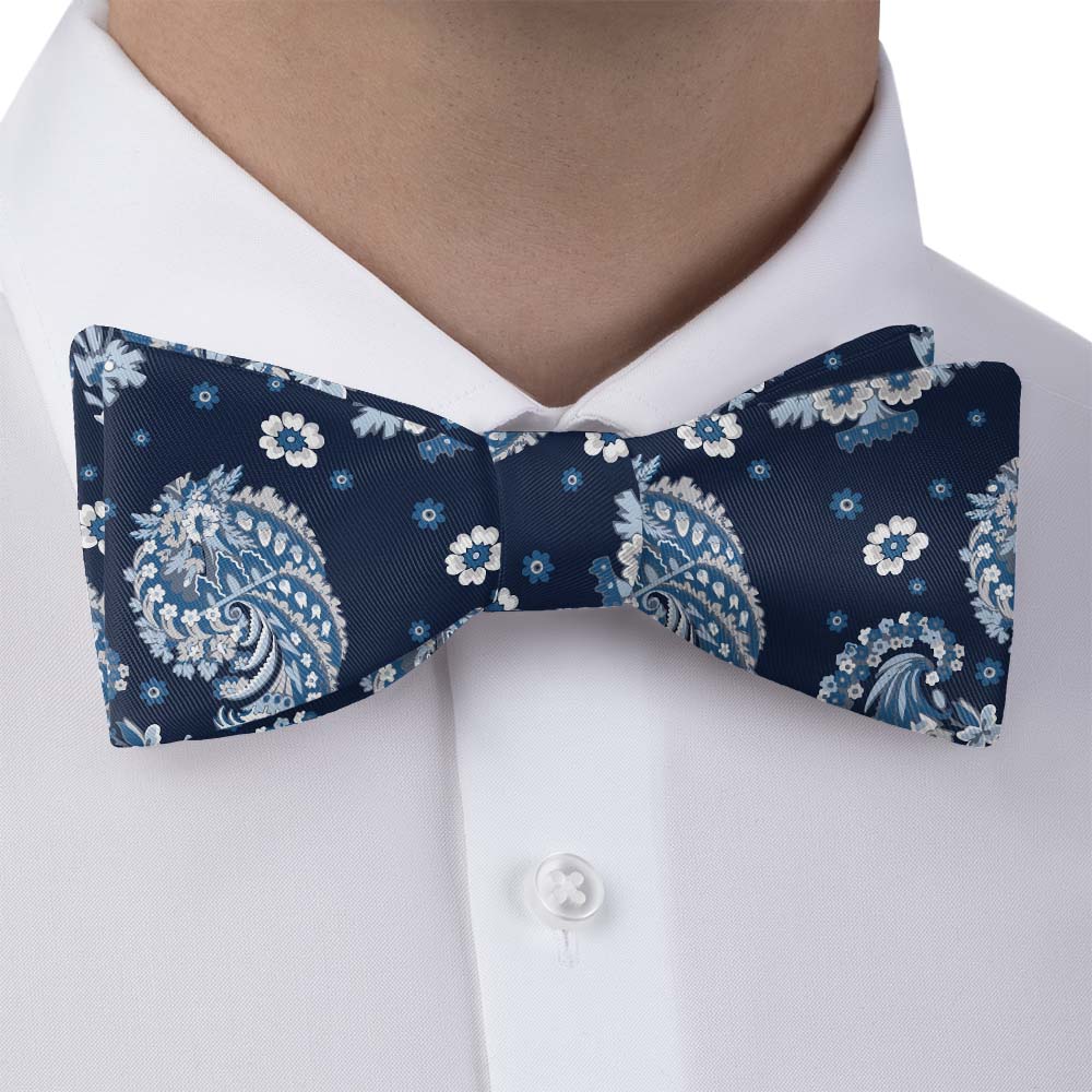 Navy blue bow tie with white floral patterns on a white shirt