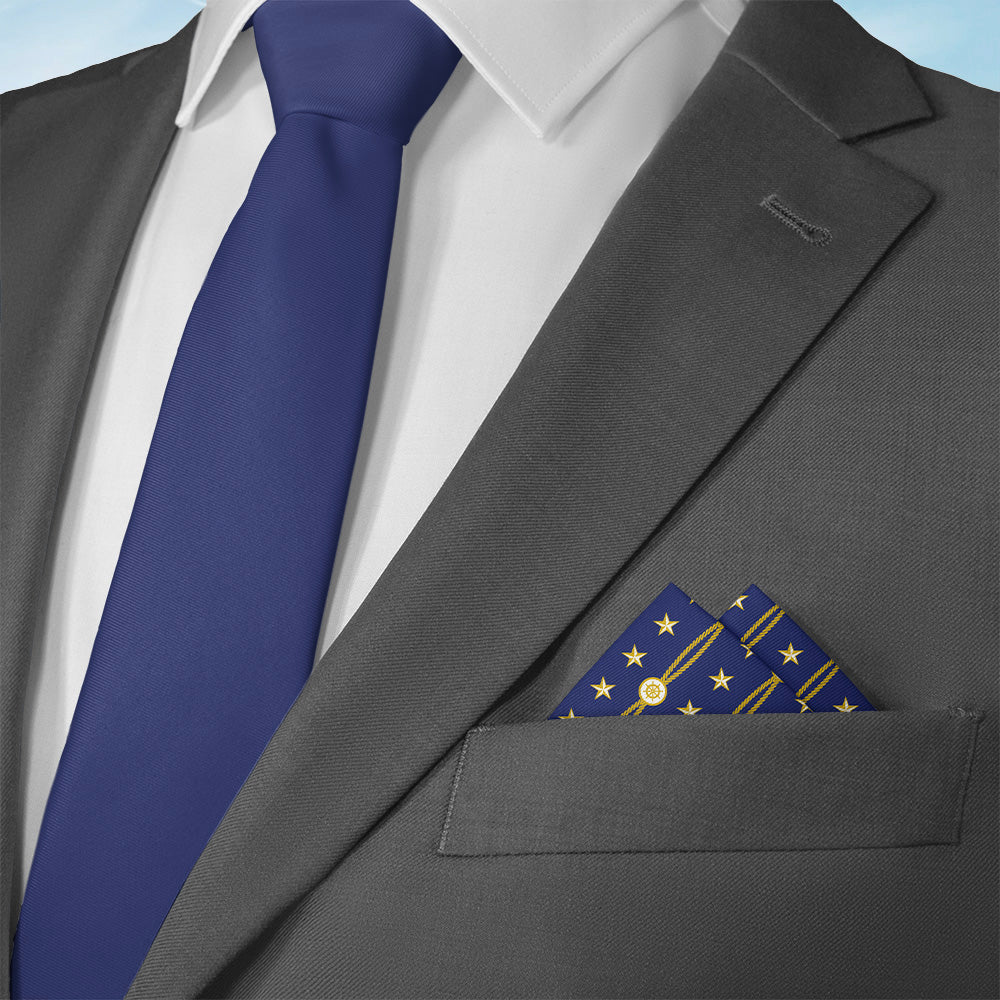 Gray suit with a blue tie and military pocket square on a light blue background