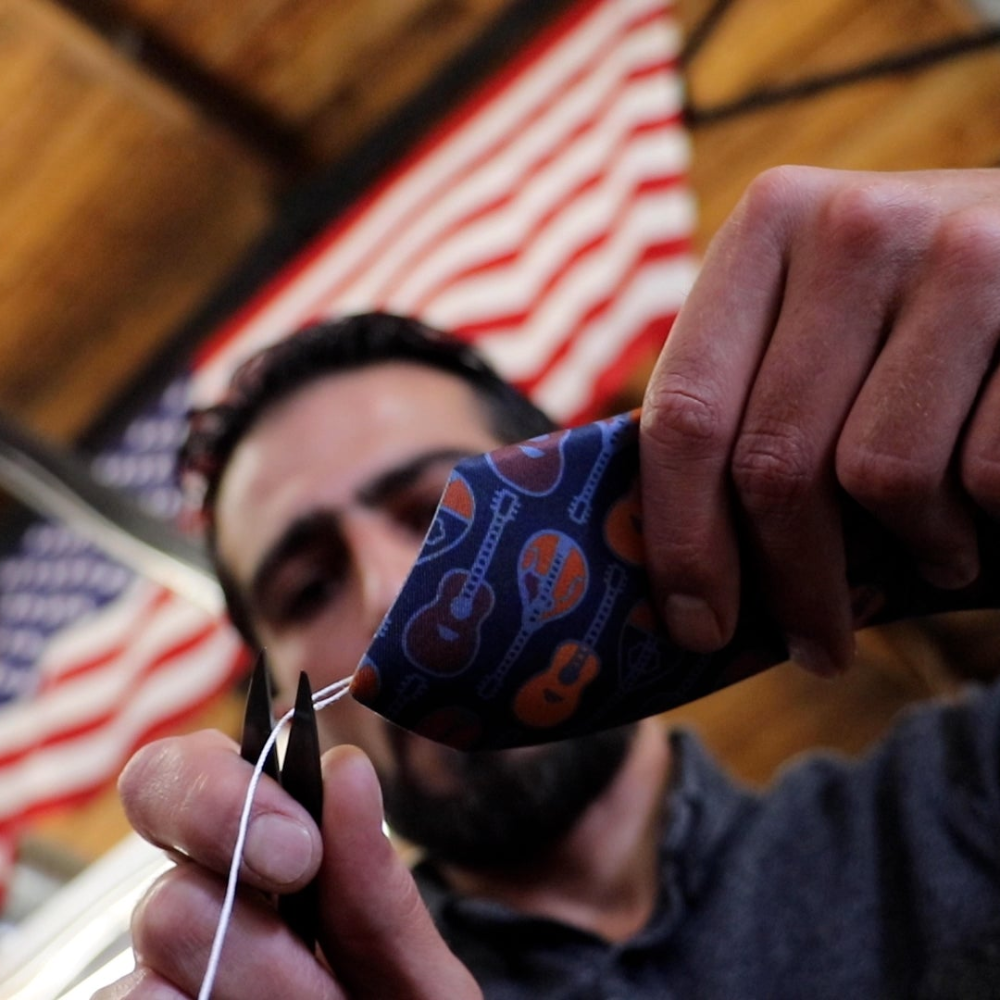 Man trimming a necktie in American manufacturing space