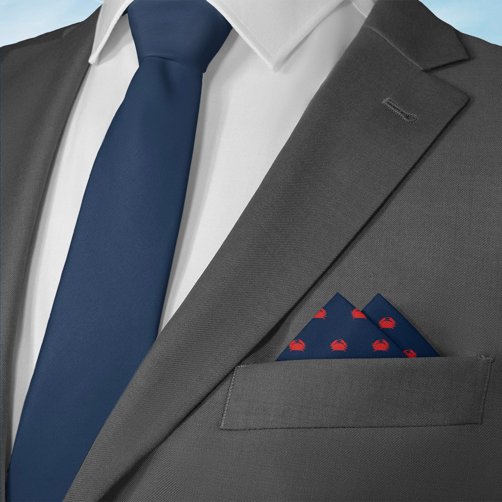 Gray suit with a blue tie and matching nautical crab pocket square on a light blue background