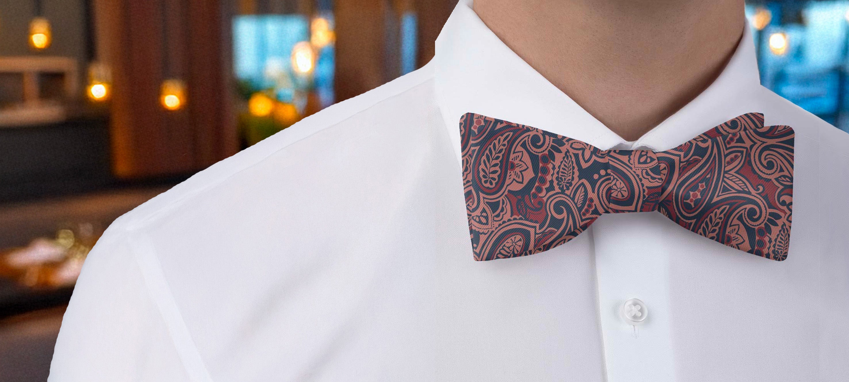 Person wearing a white shirt with a paisley patterned bow tie in an indoor setting
