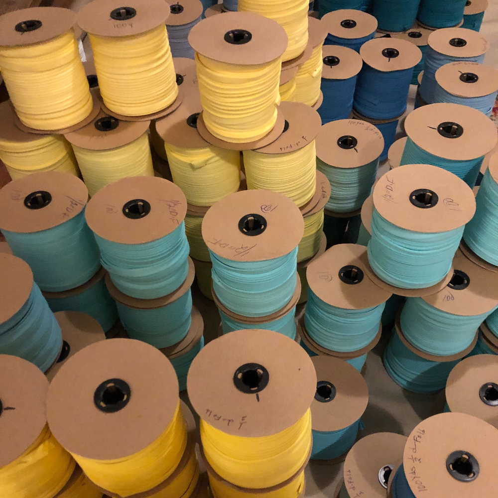 multiple stacked spools of yellow and blue thread