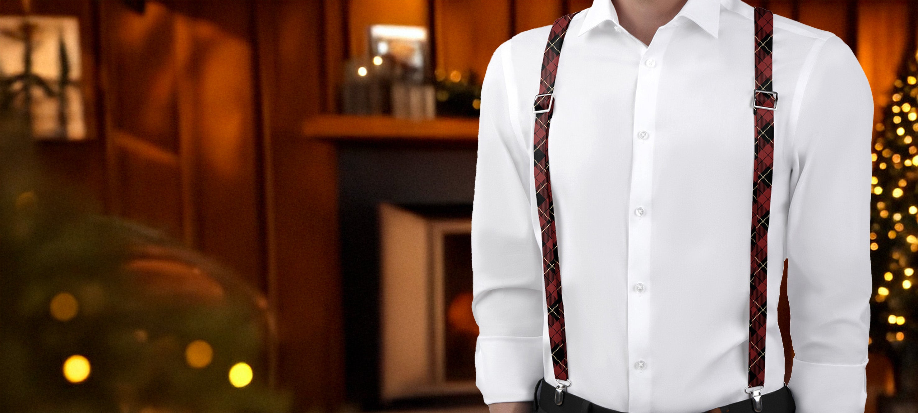 Person wearing a white shirt and plaid suspenders with a blurred bookshelf and Christmas tree in the background