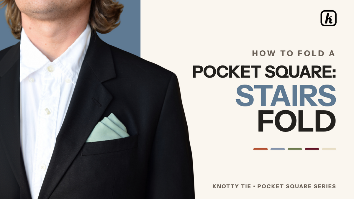 Load video: The "stairs fold" is an advanced pocket square technique characterized by its layered, architectural appearance with clean, geometric lines. To achieve this look, follow these steps:Initial Setup: Lay the pocket square flat with the printed side down in a diamond shape, ensuring one point faces toward you. Fold the bottom point up to meet the top point, creating a triangle. This folded bottom edge forms the first stair.Creating the Stairs: To build the staggered effect, perform a series of small, alternating folds:Place a finger about an inch above the bottom left corner to mark the fold line.Fold the top layer of fabric down along that line, then fold that same point back up just above the bottom edge.Repeat this alternating process once more, maintaining a slight offset between each fold to create the stair-step appearance.Shaping:Carefully hold the stairs in place and flip the design over.With the triangle pointing up, fold the right corner over to meet the left.Rotate the square so the stairs point upward and the long edge is at the bottom.Fold the left and right corners behind to square off the sides.Fold the bottom behind to size the square for your pocket.Final Placement: Slide the square into your pocket with the stairs facing up and visible. Use your fingers to adjust each step so the layers remain crisp and evenly spaced.