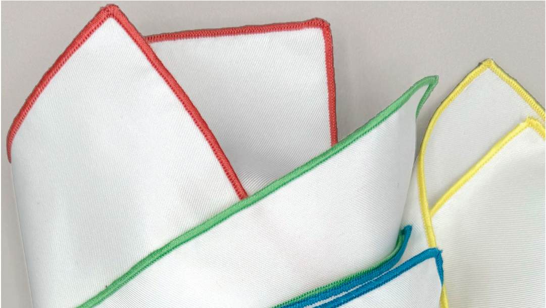 White handkerchiefs with colorful borders on a light gray background