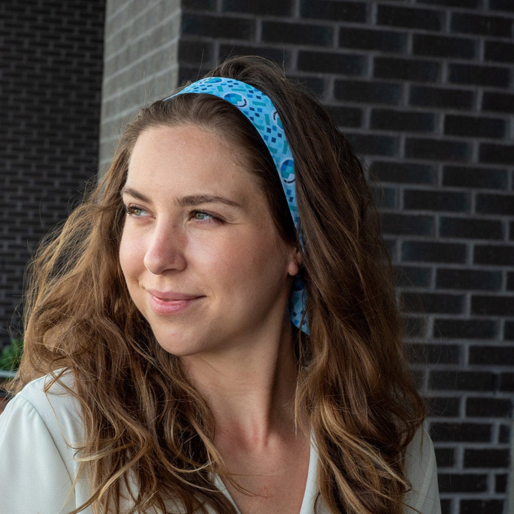 Woman wearing a blue hair scarf against a brick wall