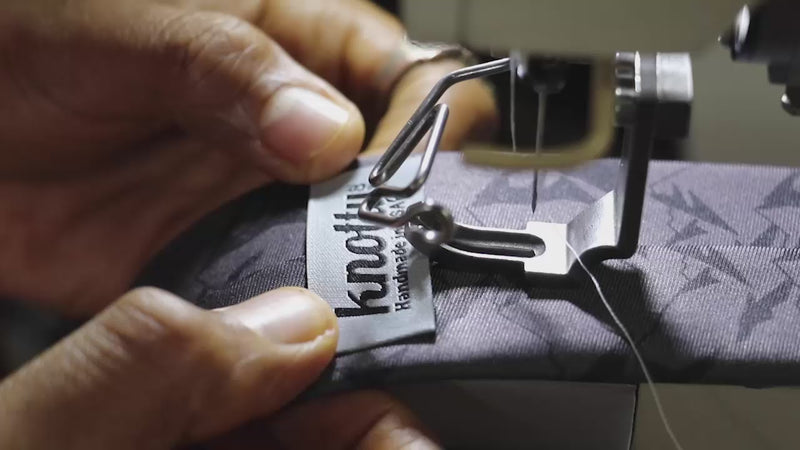 man sewing a label onto a necktie