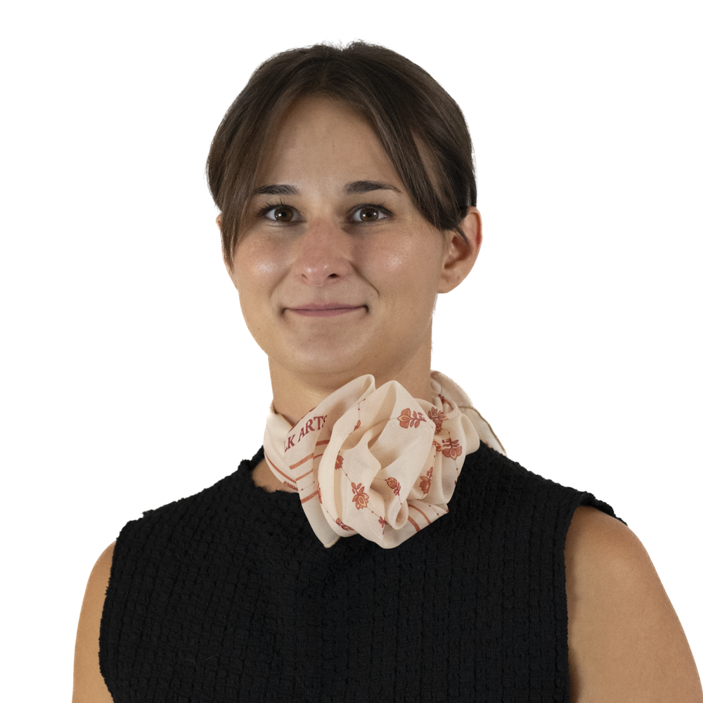 A woman wearing a square scarf styled into a rose around her neck