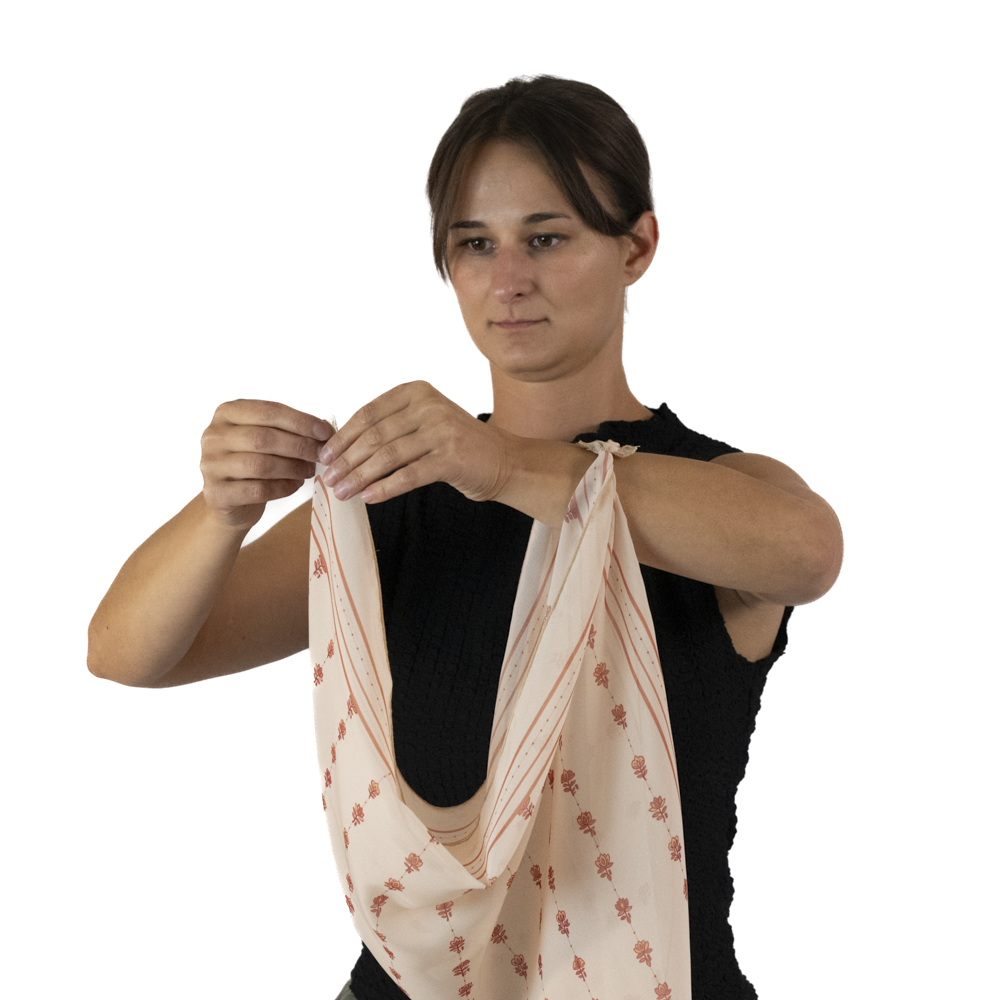 A woman moves the corner of a square scarf to her left hand