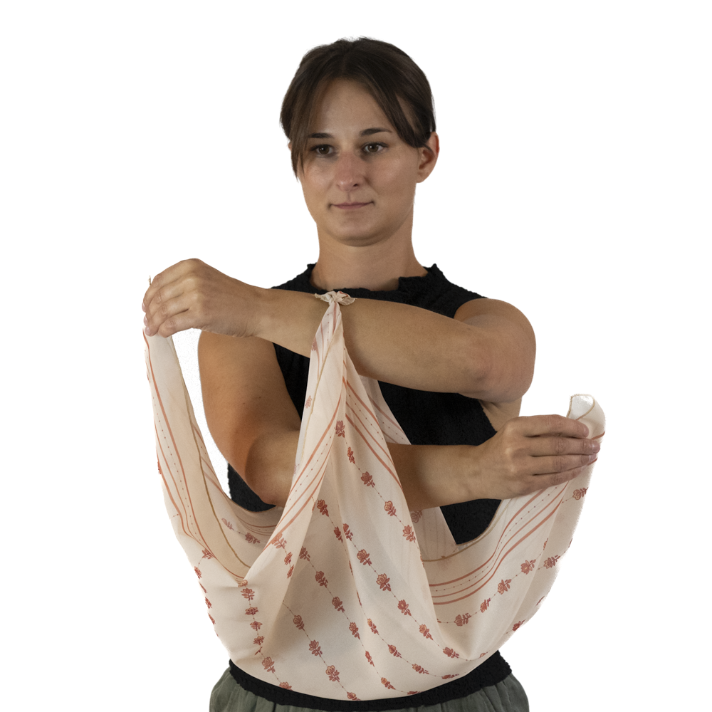 A woman uses her right hand to reach through the scarf loop, and grab the other scarf corner.