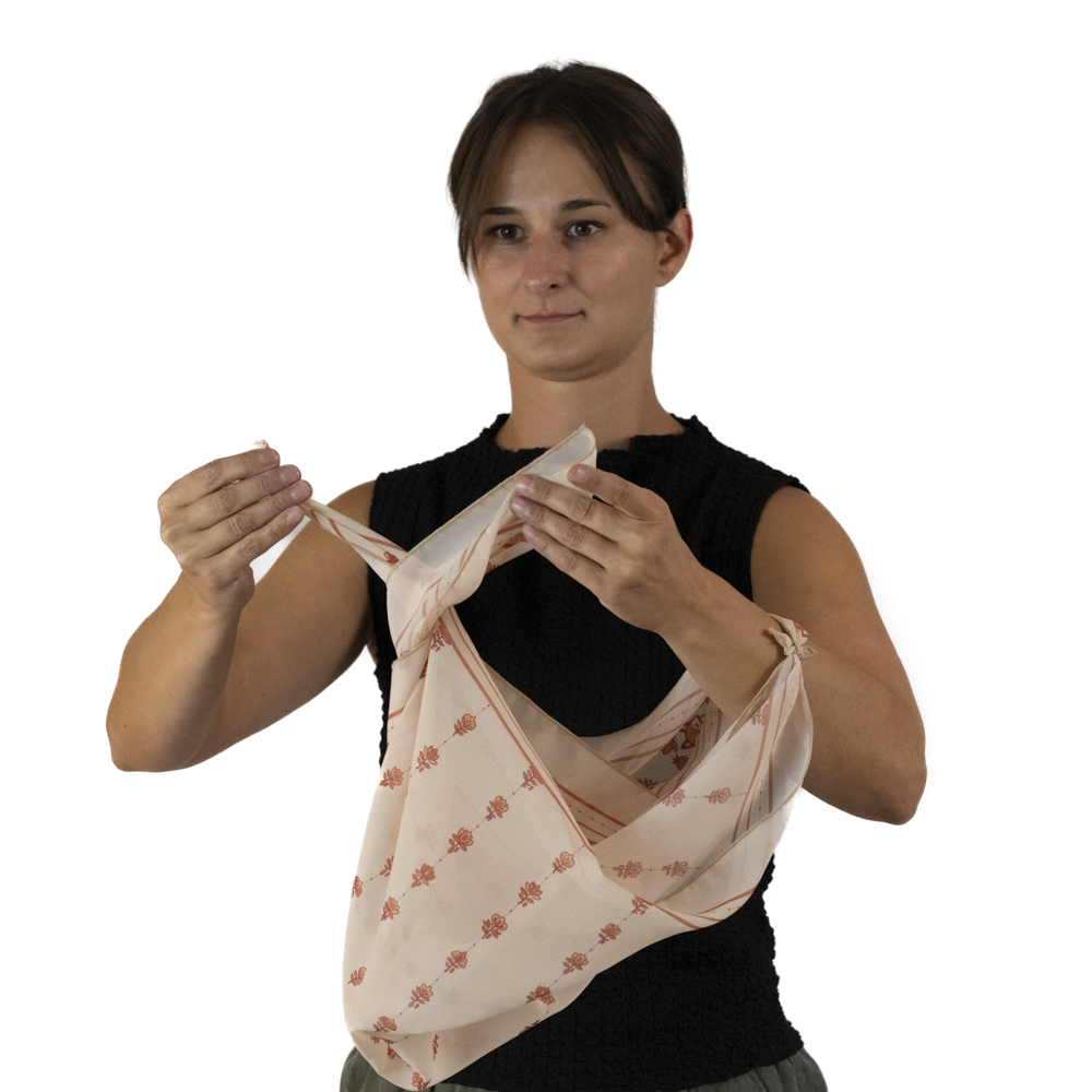 A woman demonstrates how twist the two corners of the scarf