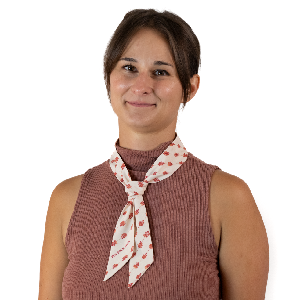 A woman wearing a cream skinny scarf tied into a simple knot around her neck.