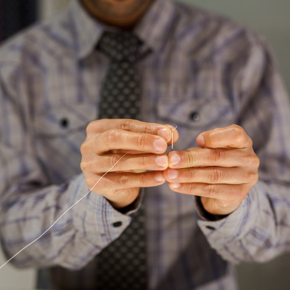 man threading a needle